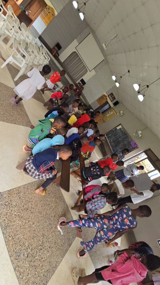Children and leaders gathered around the benches inside the church at 5 Day Club