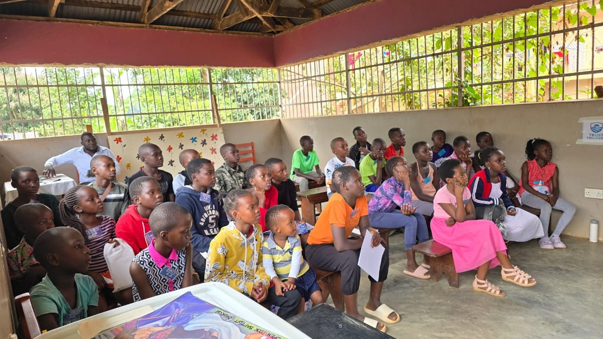 Children seated with their leaders in a covered outdoor area at 5 Day Club