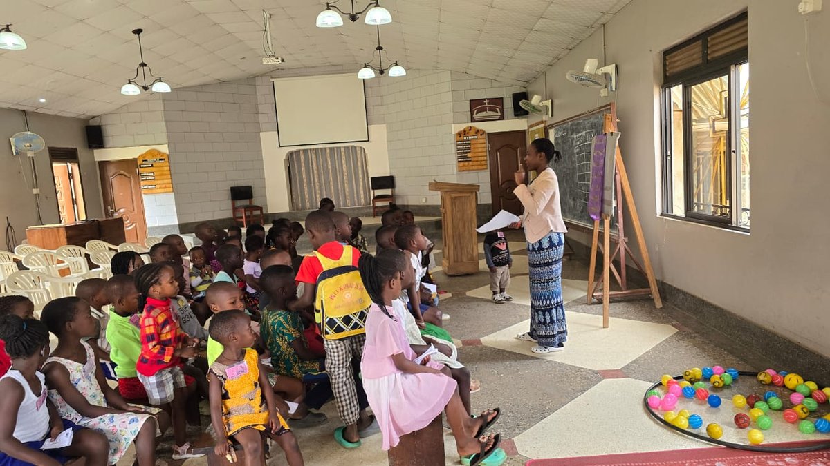 A leader speaking to children seated in the sanctuary at 5 Day Club