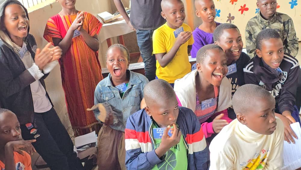 Children smiling and joining in with a group activity at 5 Day Club