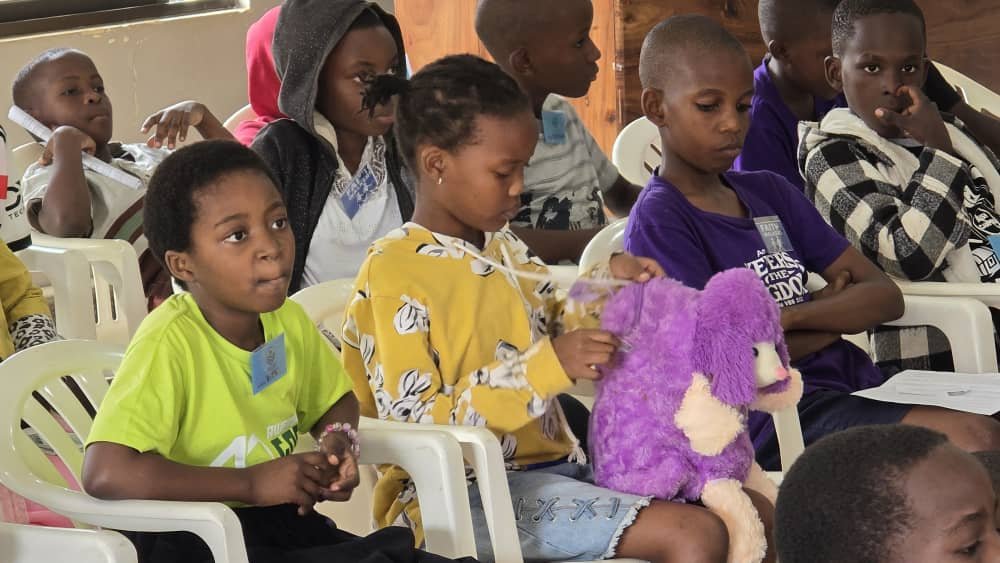 Children listening together while seated in the sanctuary at 5 Day Club