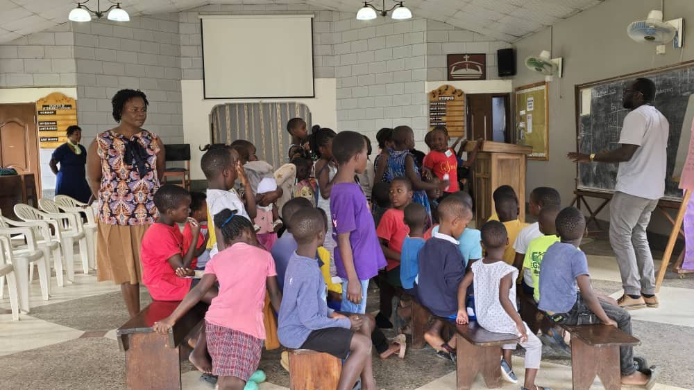 Children and leaders taking part in an activity among the church chairs at 5 Day Club