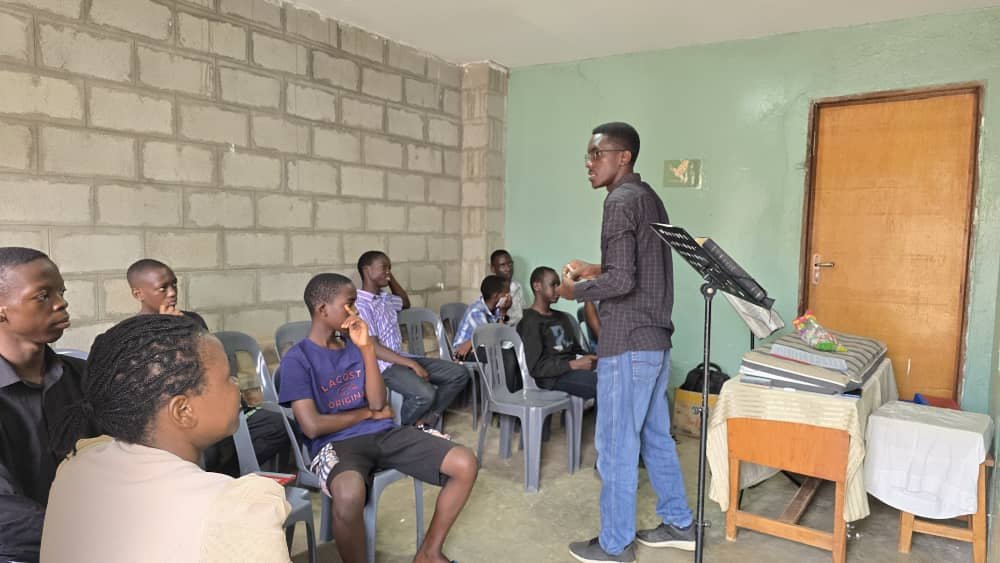 A leader teaching a group beside a chalkboard at 5 Day Club