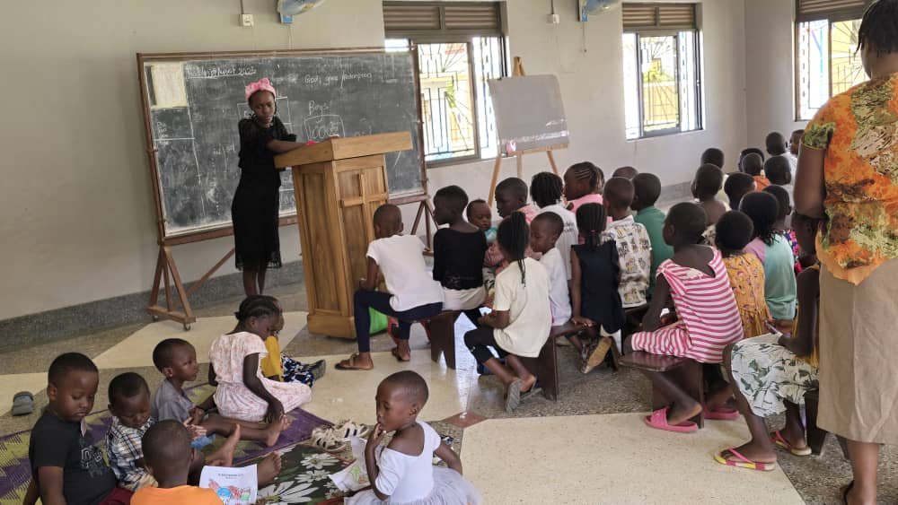 Children seated in front of a leader teaching beside a chalkboard at 5 Day Club
