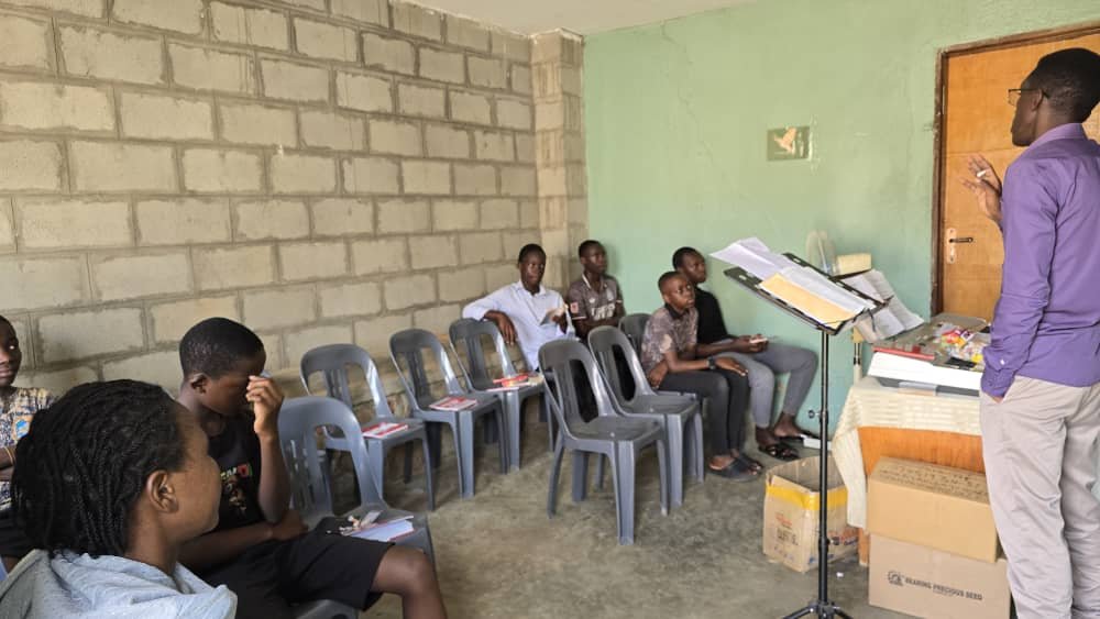 A leader teaching children gathered in a small group at 5 Day Club